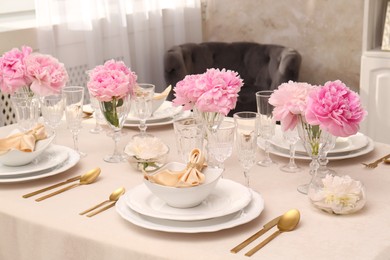 Stylish table setting with beautiful peonies and fabric napkins indoors