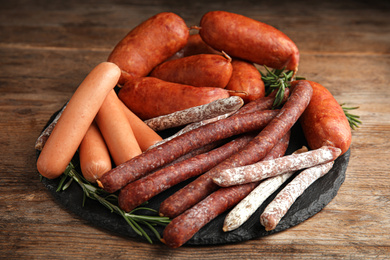 Different tasty sausages served on wooden table