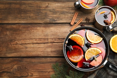 Delicious mulled wine and ingredients on wooden table, flat lay. Space for text