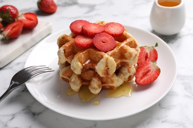 Photo of Delicious Belgian waffles with strawberries and honey on white marble table, closeup