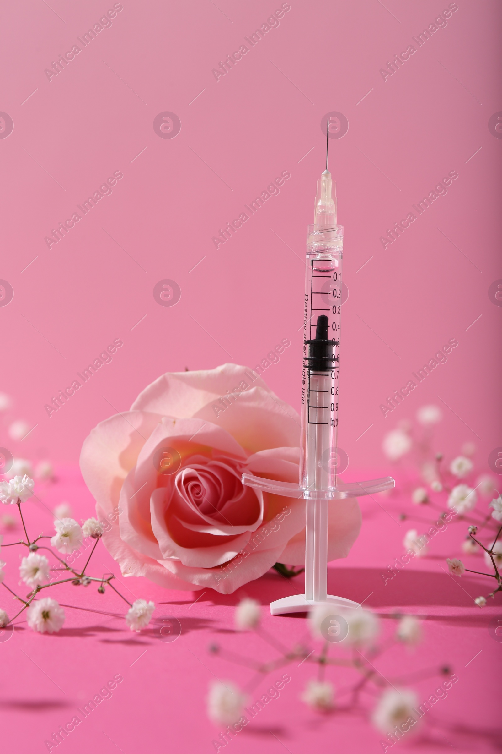 Photo of Cosmetology. Medical syringe, rose and gypsophila flowers on pink background