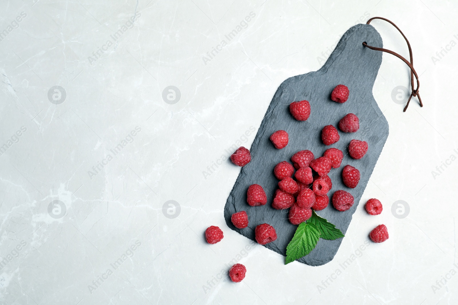 Photo of Slate plate with ripe aromatic raspberries on table, top view