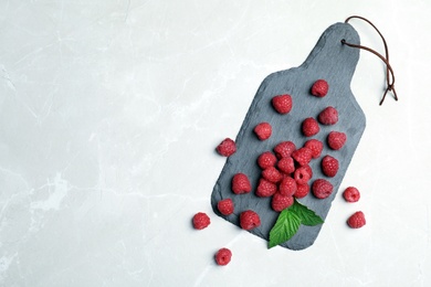 Slate plate with ripe aromatic raspberries on table, top view