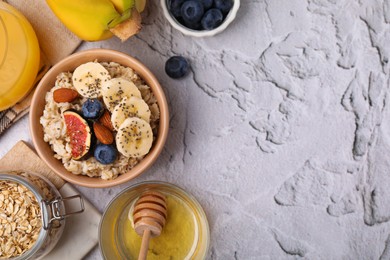 Photo of Bowl of oatmeal with blueberries, almonds, banana and fig pieces on white textured table, flat lay. Space for text