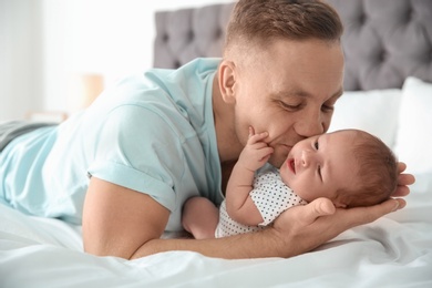 Photo of Man with his newborn baby on bed