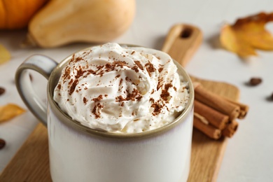 Photo of Cup with tasty pumpkin spice latte on light table, closeup