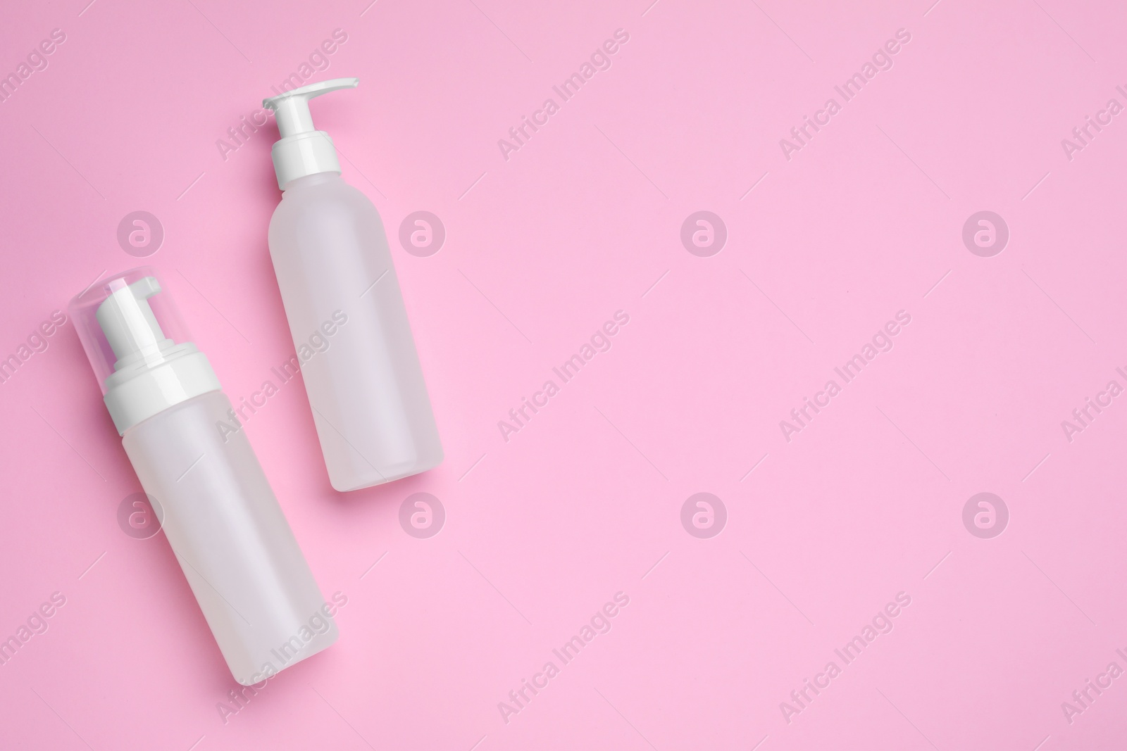 Photo of Different cleansers on pink background, flat lay with space for text. Cosmetic product