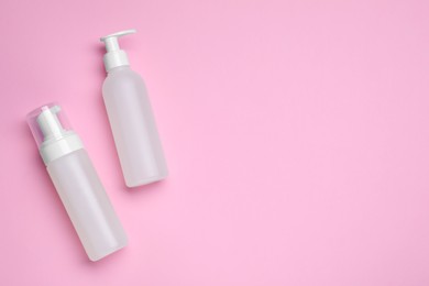 Different cleansers on pink background, flat lay with space for text. Cosmetic product