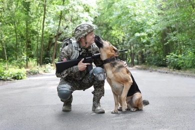 Photo of Man in military uniform with German shepherd dog, outdoors