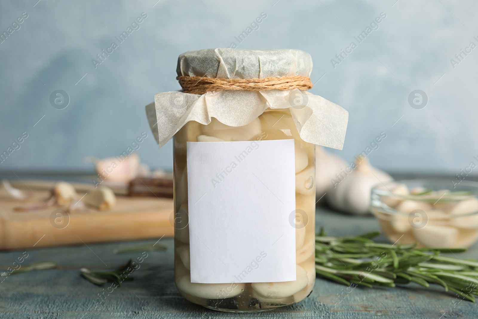 Photo of Composition with jar of pickled garlic on blue wooden table