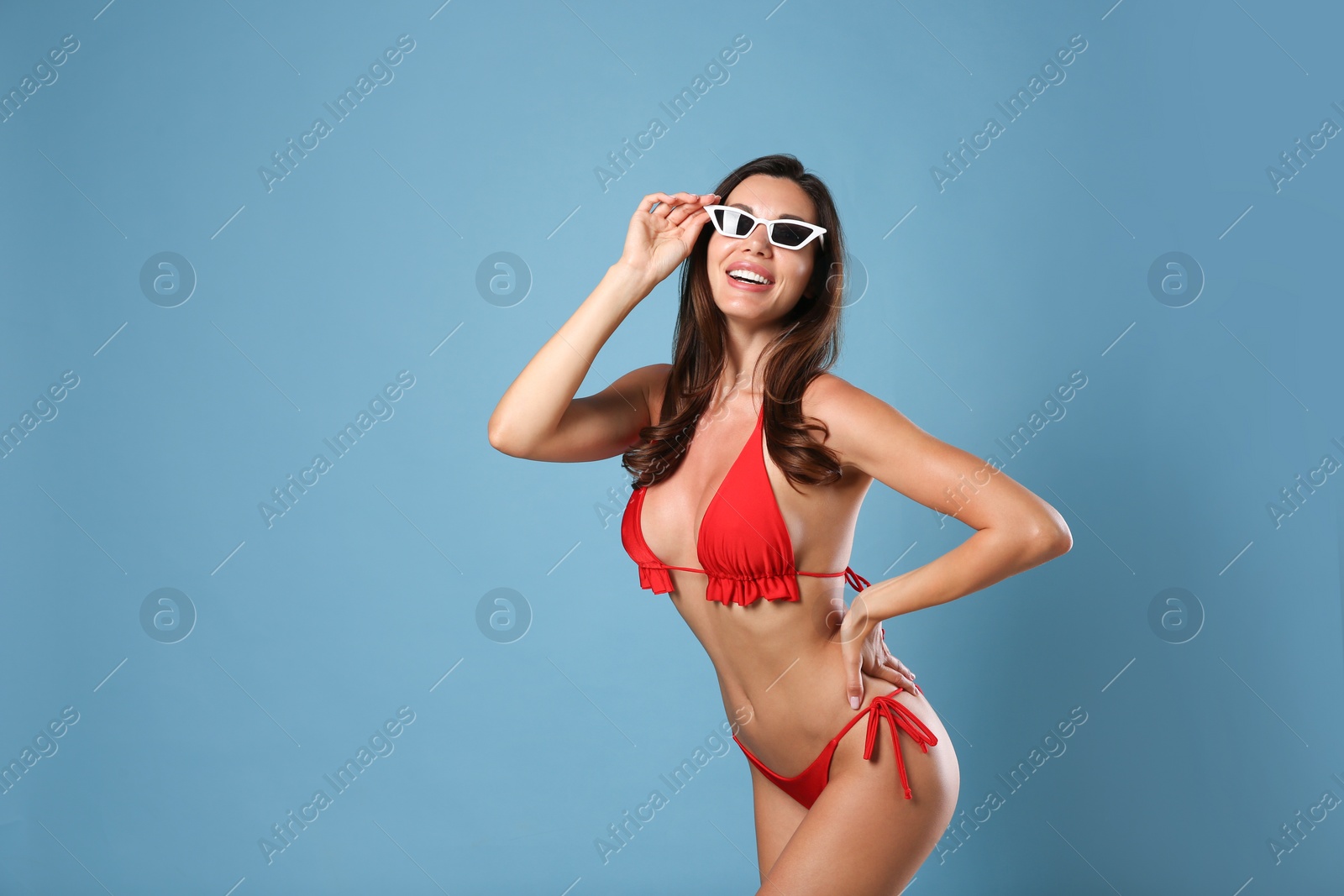 Photo of Beautiful woman in stylish bikini and sunglasses on blue background. Space for text