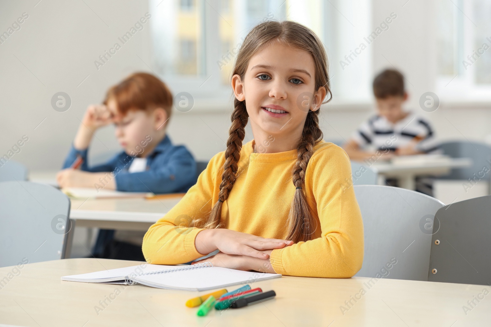 Photo of Portrait of smiling little girl studying in classroom at school