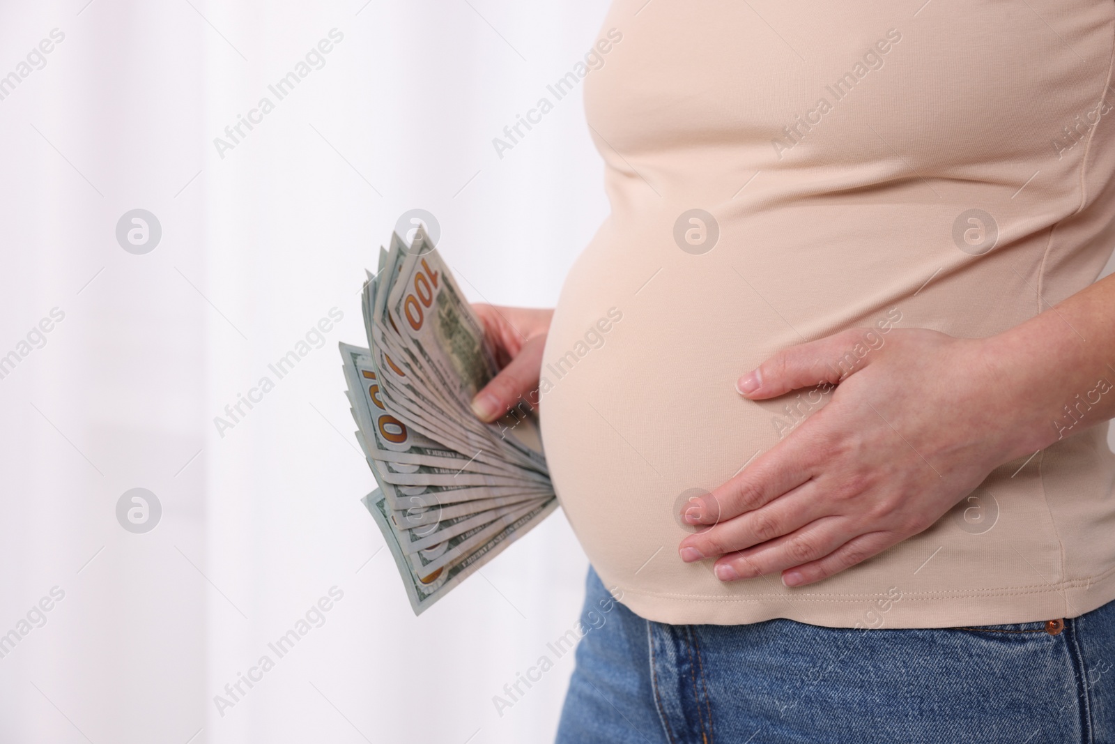 Photo of Surrogate mother. Pregnant woman with dollar banknotes indoors, closeup. Space for text