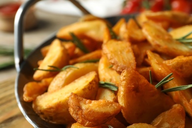 Photo of Metal dish with baked potatoes and rosemary, closeup