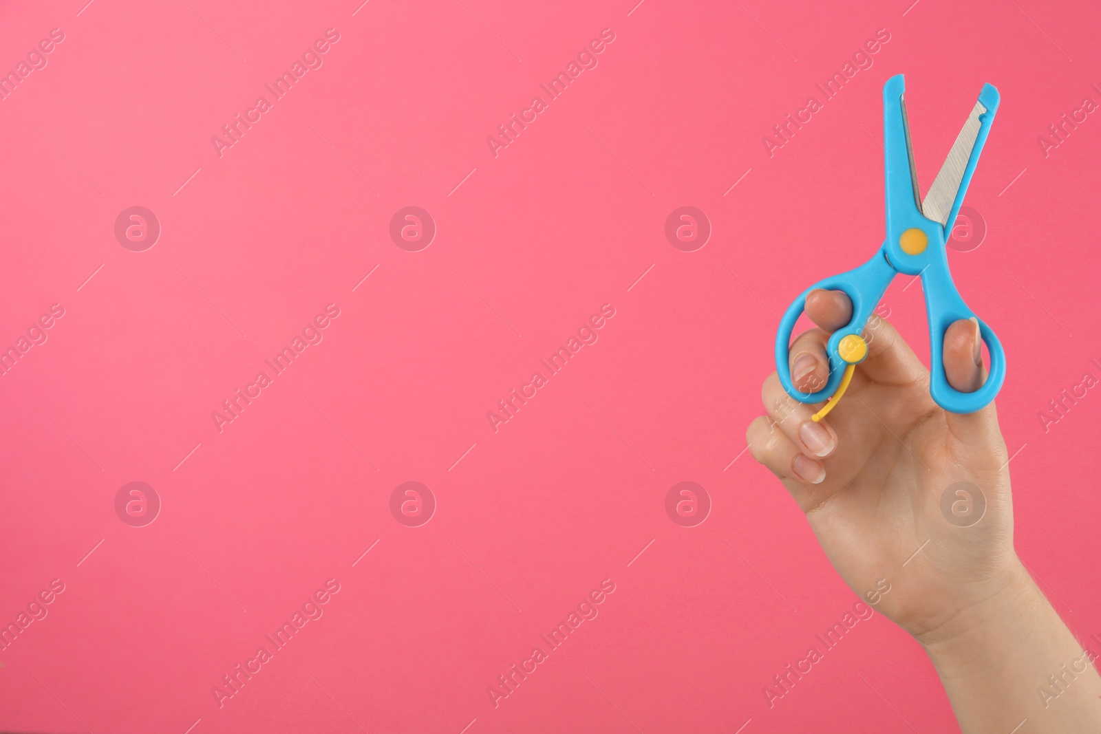 Photo of Woman holding small scissors on pink background, closeup. Space for text