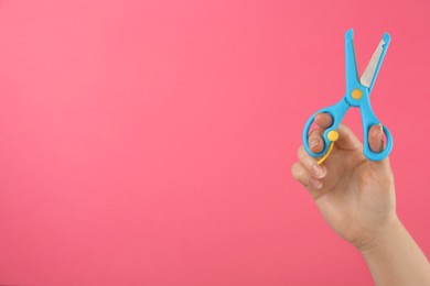 Photo of Woman holding small scissors on pink background, closeup. Space for text