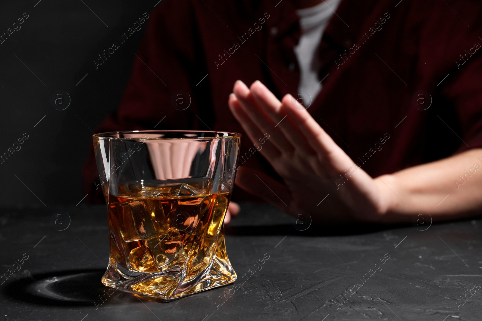 Photo of Alcohol addiction. Woman refusing glass of whiskey at dark textured table, closeup