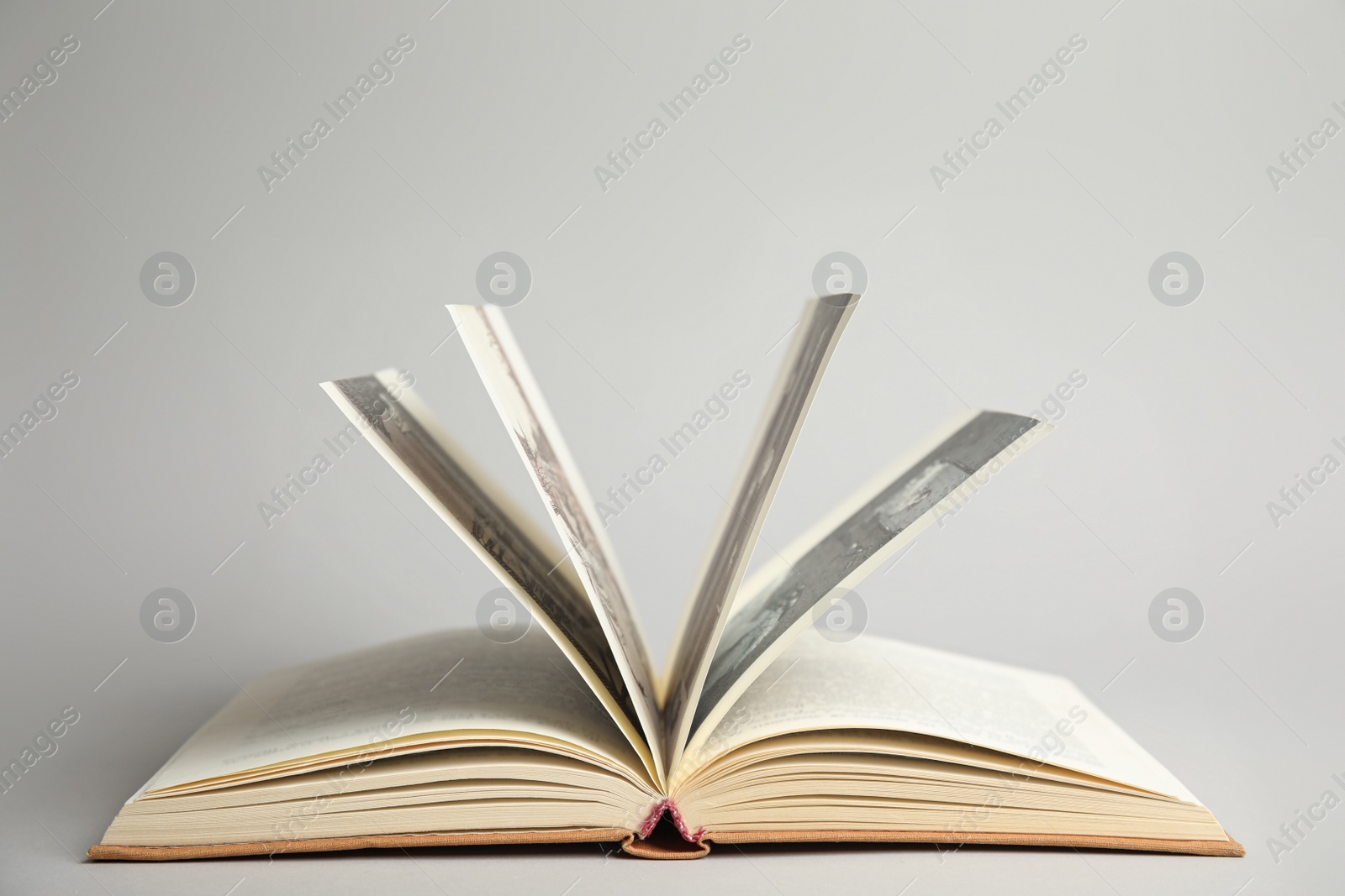Photo of Open old hardcover book on light grey background