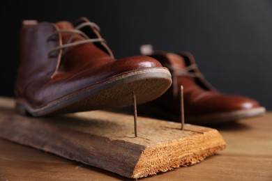 Metal nails in wooden plank and shoes on table