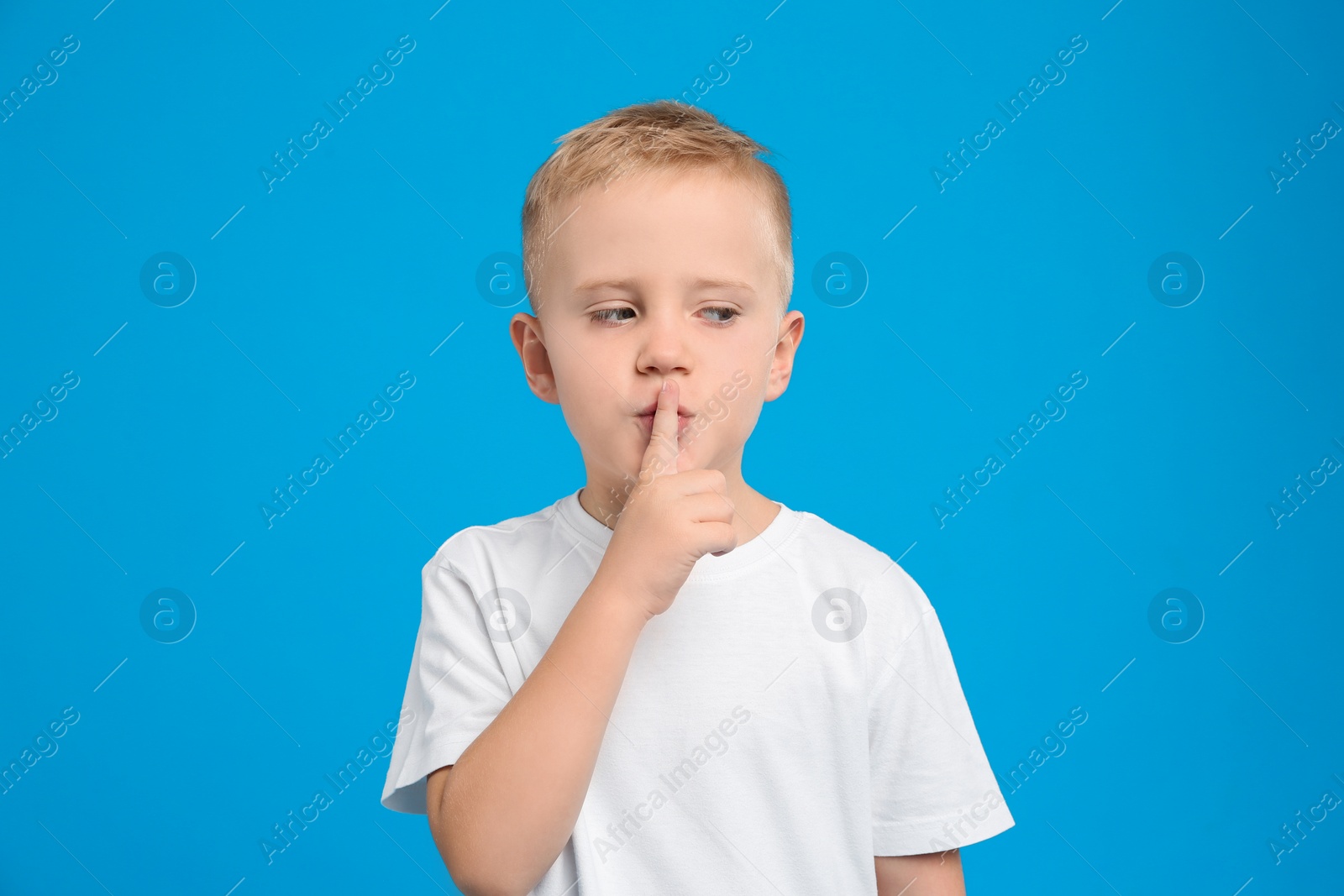 Photo of Portrait of cute little boy on light blue background