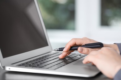 Photo of Woman working on laptop at table, closeup. Electronic document management