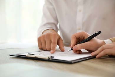 Businesspeople working with document at table indoors, closeup