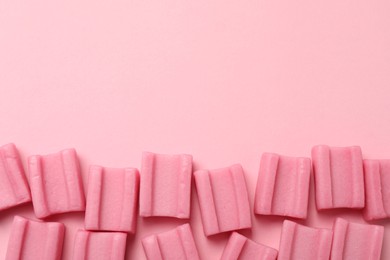 Photo of Tasty chewing gums on pink background, flat lay. Space for text