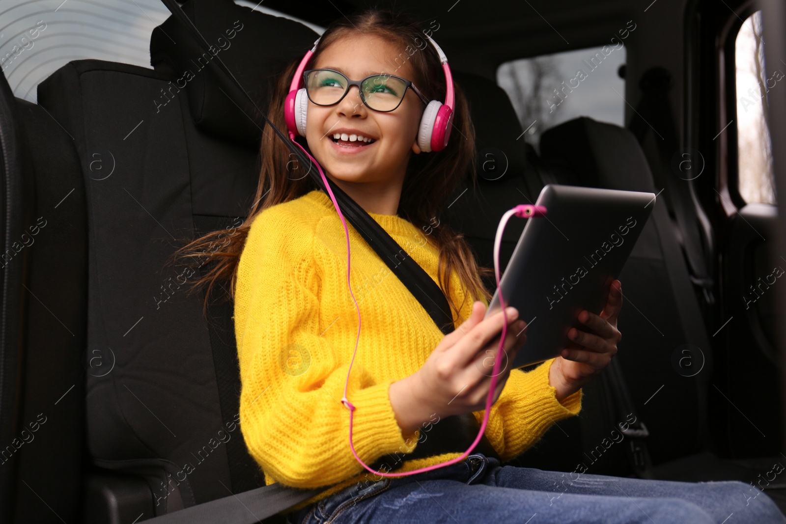 Photo of Cute little girl listening to audiobook in car