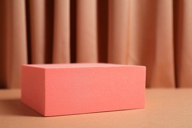 Photo of Stand on table against light brown curtain, closeup. Stylish presentation for product