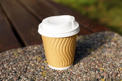 Photo of Paper cup on parapet outdoors, closeup. Coffee to go