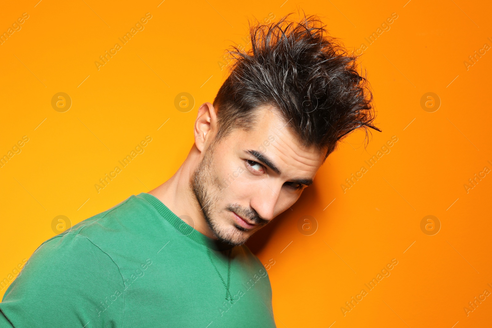 Photo of Young man with trendy hairstyle posing on color background