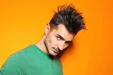 Photo of Young man with trendy hairstyle posing on color background