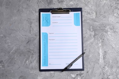 Photo of Medical prescription form with empty fields and pen on grey textured table, top view
