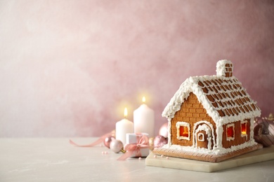 Photo of Beautiful gingerbread house decorated with icing on light table, space for text
