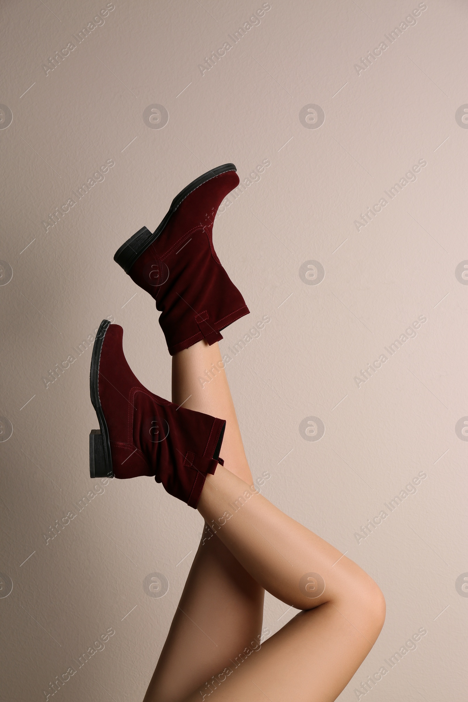 Photo of Woman wearing stylish boots on beige background, closeup