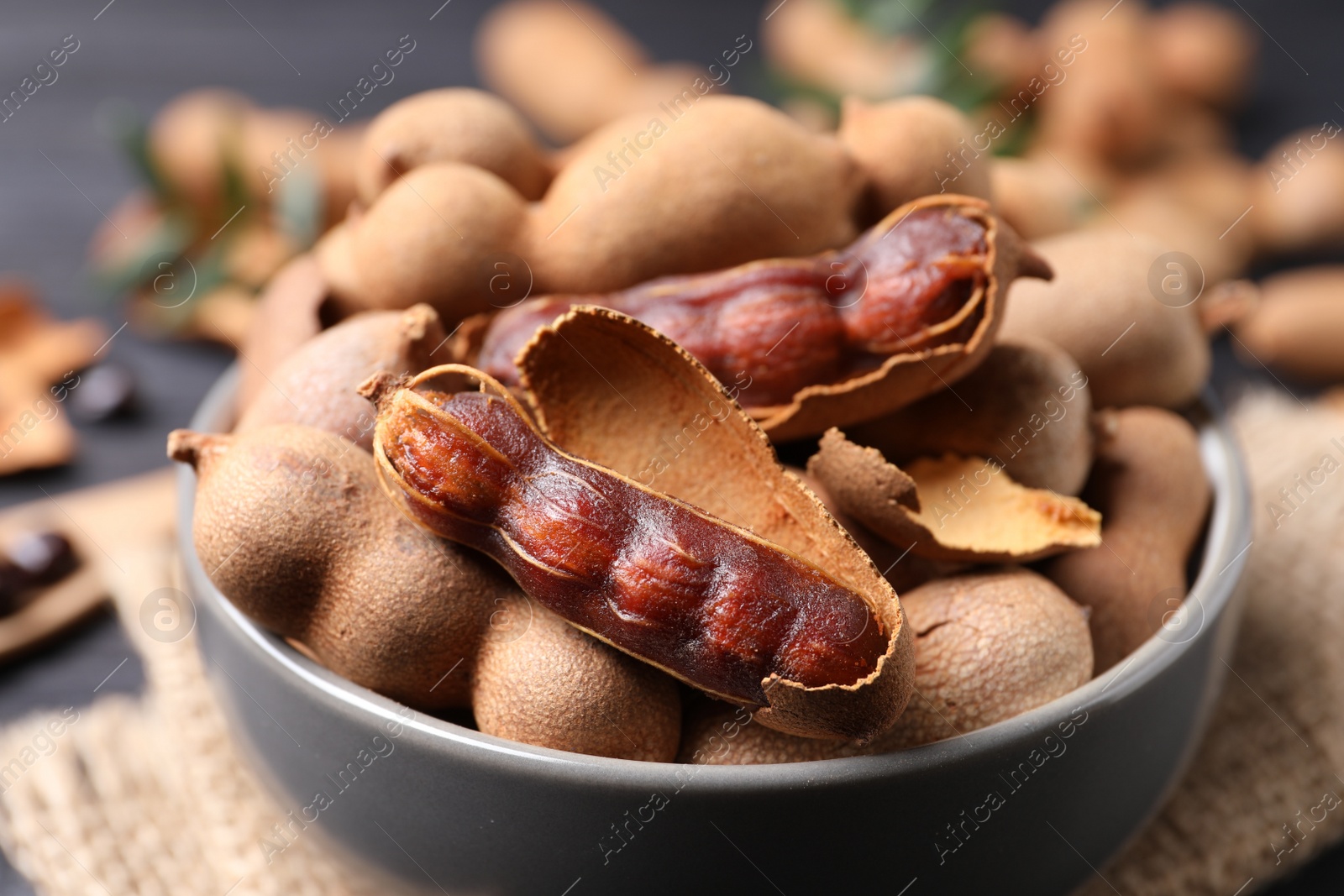 Photo of Delicious ripe tamarinds in ceramic bowl on table, closeup