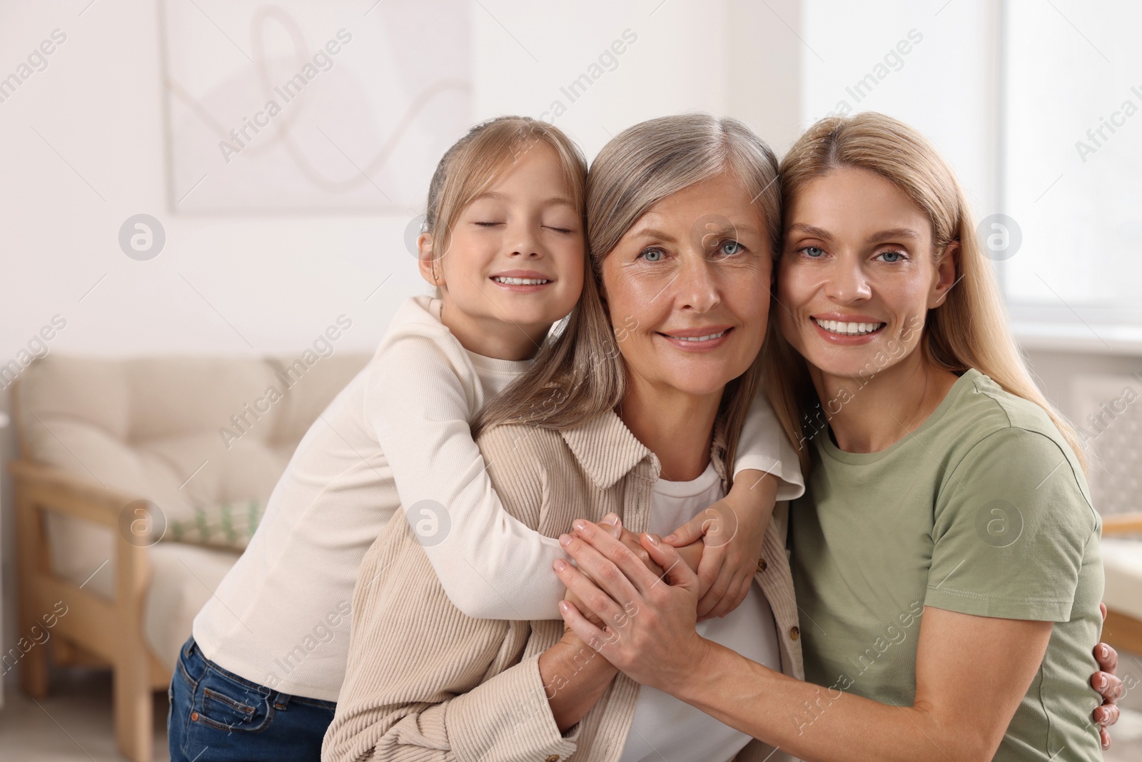 Photo of Three generations. Happy grandmother, her daughter and granddaughter at home