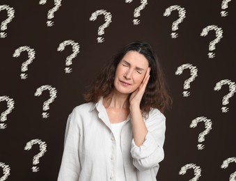 Amnesia. Confused woman and question marks on brown background