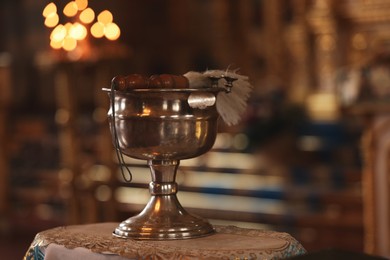 Photo of Silver vessel with holy water and brush on stand in church, space for text. Baptism ceremony