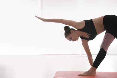 Photo of Young woman practicing extended triangle asana in yoga studio. Utthita Trikonasana pose