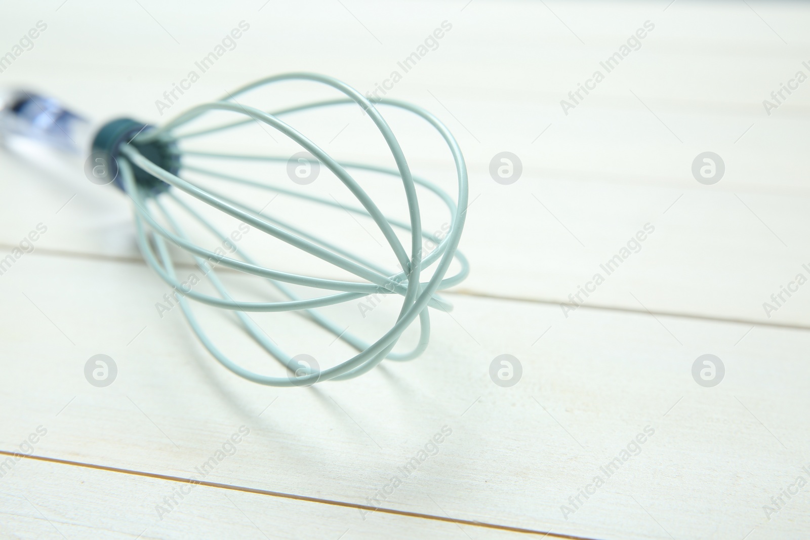 Photo of One whisk on white wooden table, closeup. Space for text