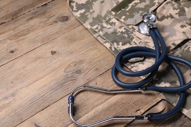 Photo of Stethoscope and military uniform on wooden table, space for text
