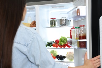 Young woman near modern refrigerator, selective focus