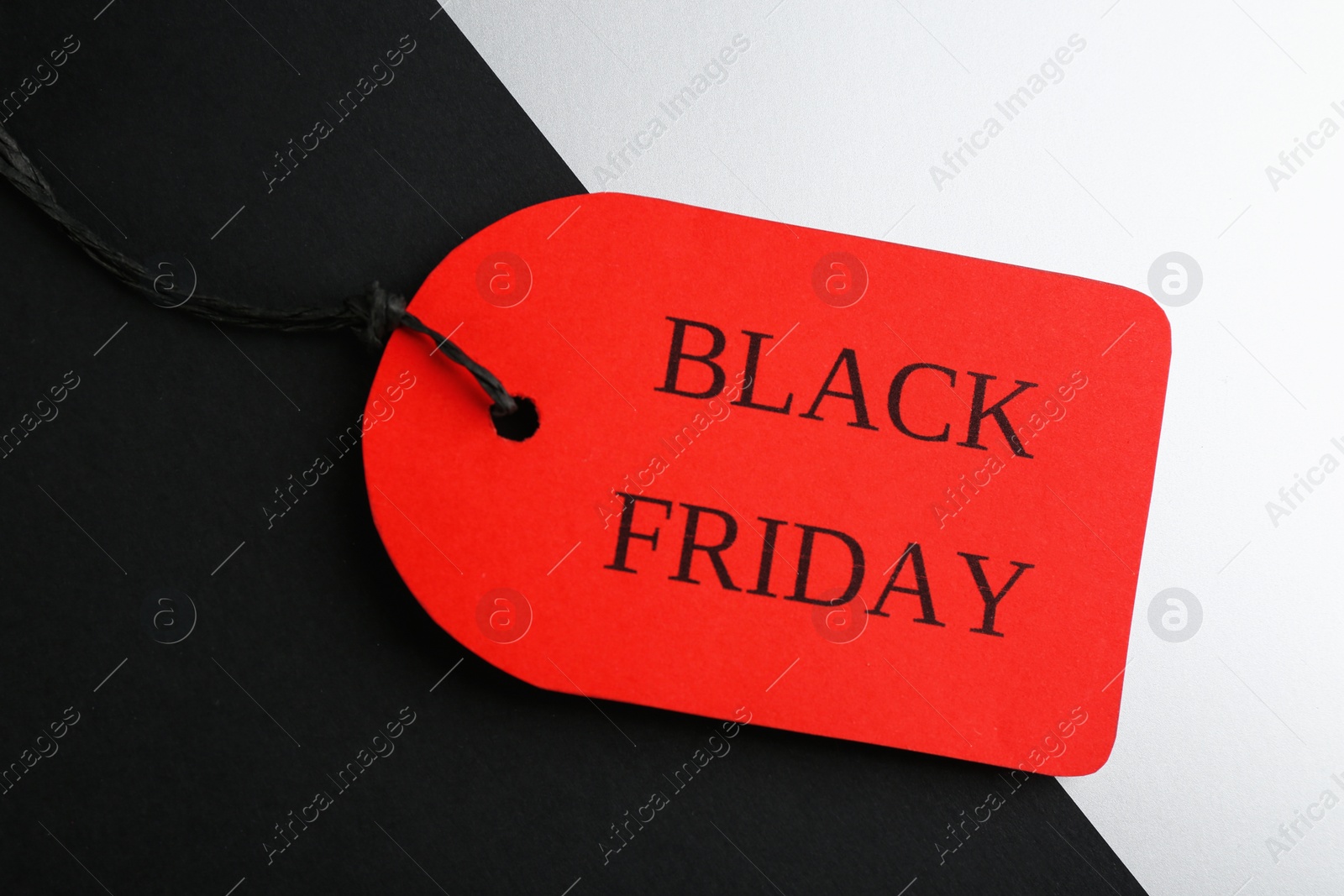 Photo of Red tag with words BLACK FRIDAY on color background, top view