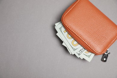 Photo of Stylish brown leather wallet with dollar banknotes on light grey background, top view. Space for text