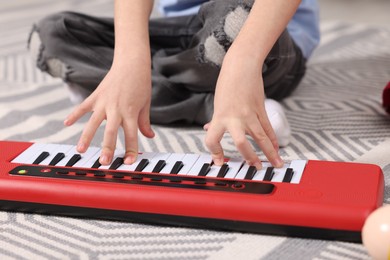 Photo of Little boy playing toy piano at home, closeup