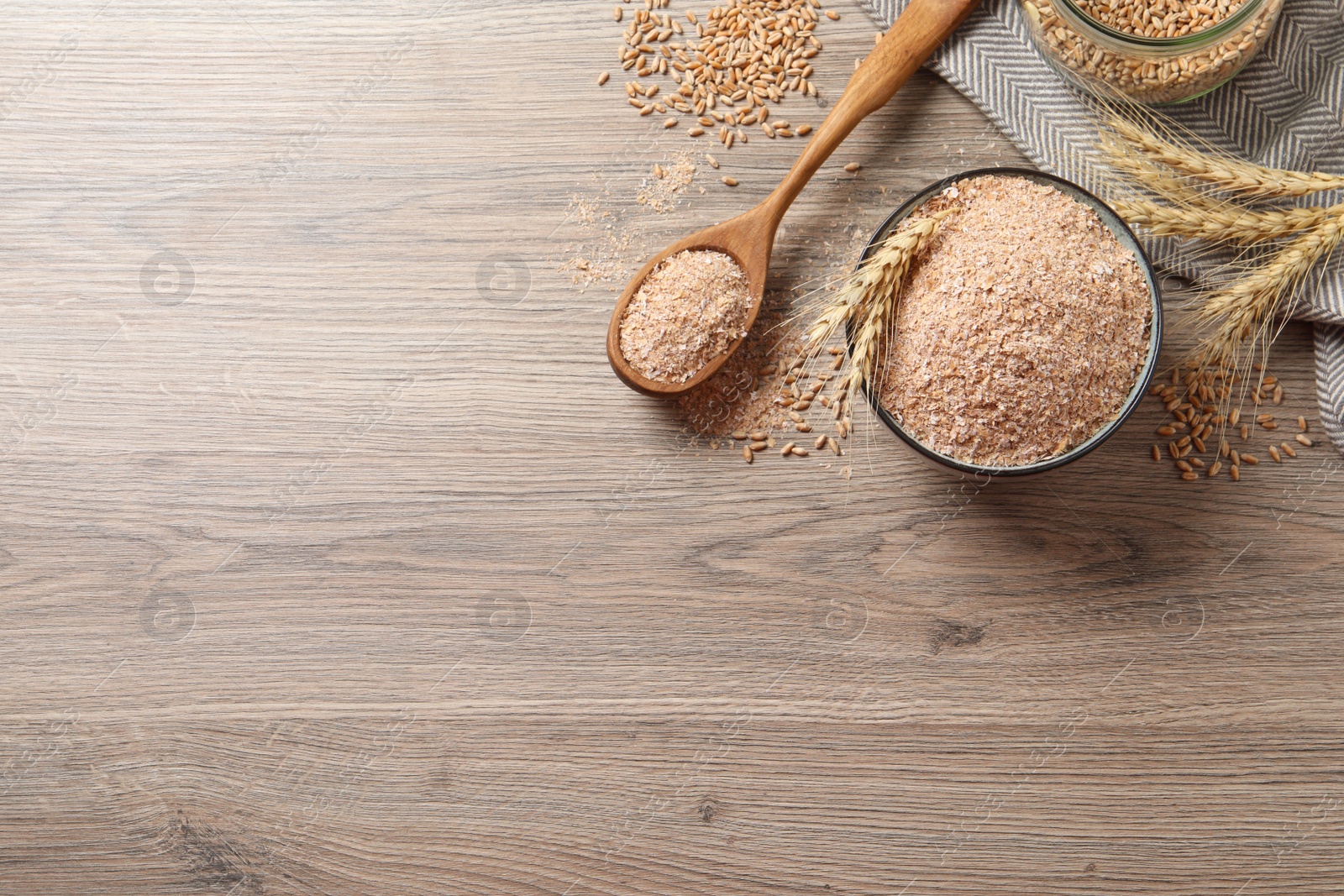 Photo of Wheat bran, kernels and spikelets on wooden table, flat lay. Space for text