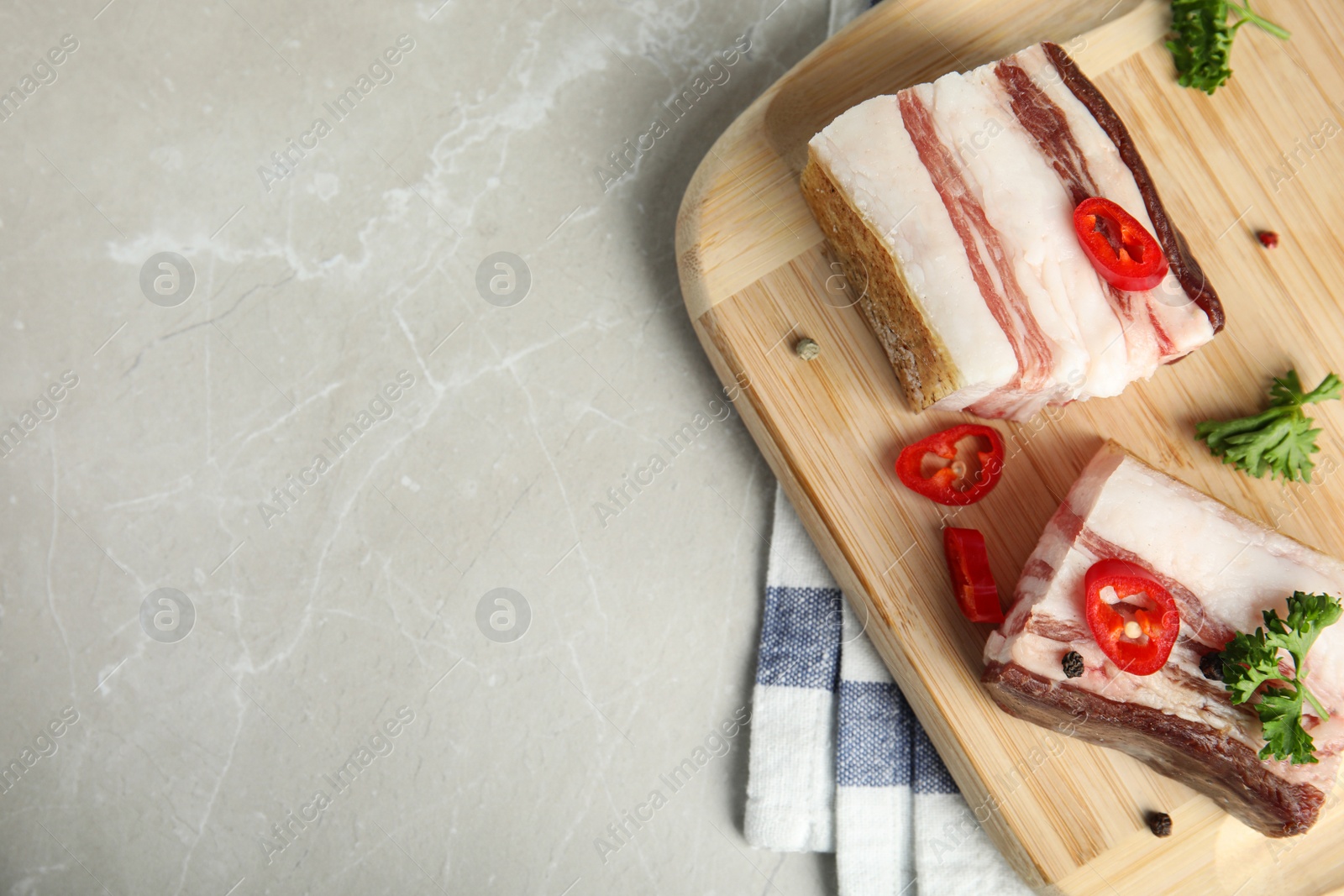 Photo of Board with bacon and pepper on grey stone background, flat lay. Space for text