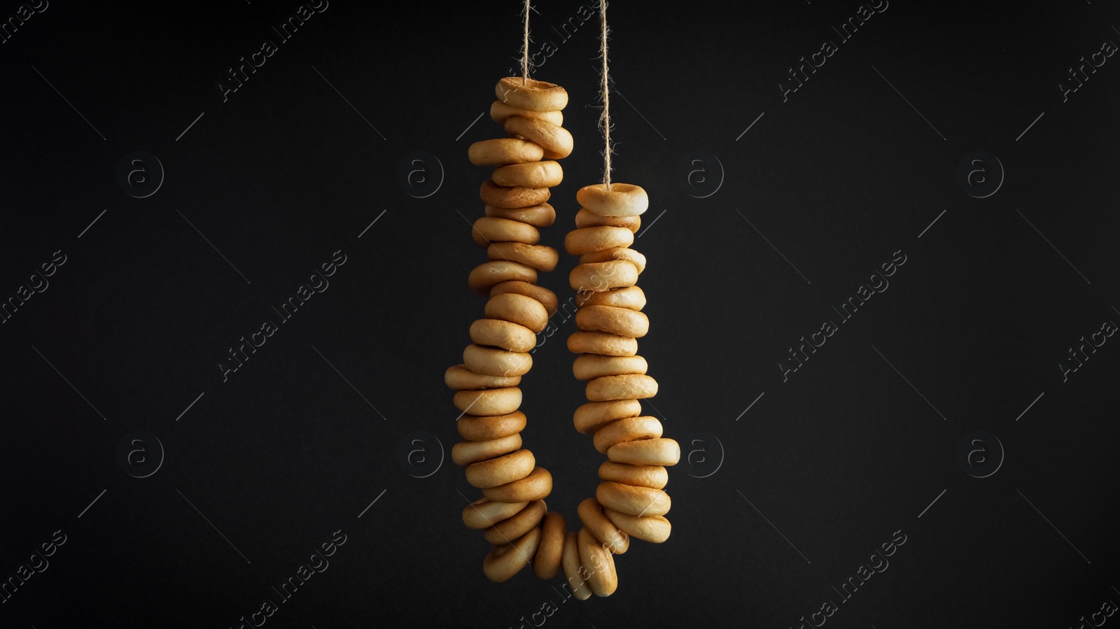 Photo of Bunch of delicious ring shaped Sushki (dry bagels) hanging on black background