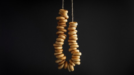 Bunch of delicious ring shaped Sushki (dry bagels) hanging on black background